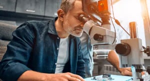 Man looking through microscopes in an industrial setting